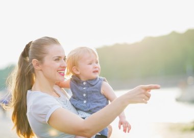 Mother showing something to baby clipart