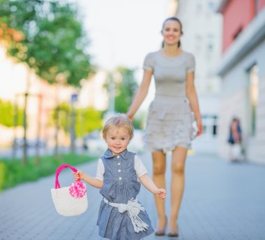 Happy baby walking with mom in city clipart