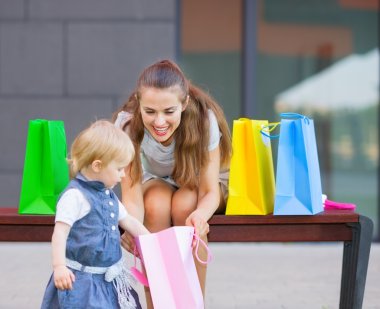 Mother and baby examines purchases after shopping clipart