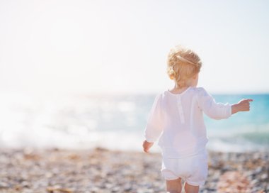 Bebek Plajda yürüyor. arka görünüm