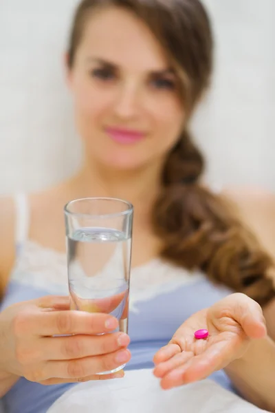 Крупный план на таблетки и стакан воды в руке счастливой женщины — стоковое фото