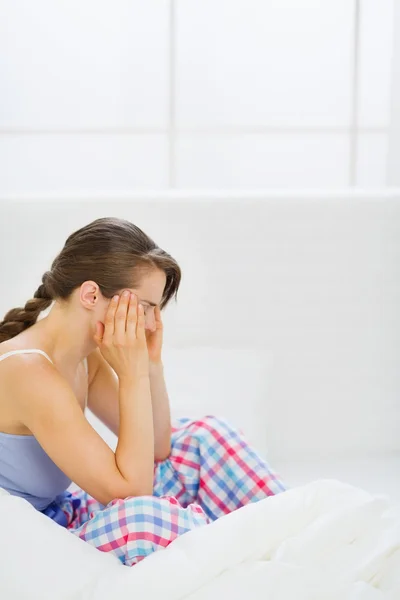 Mädchen mit Kopfschmerzen auf Bett sitzend — Stockfoto