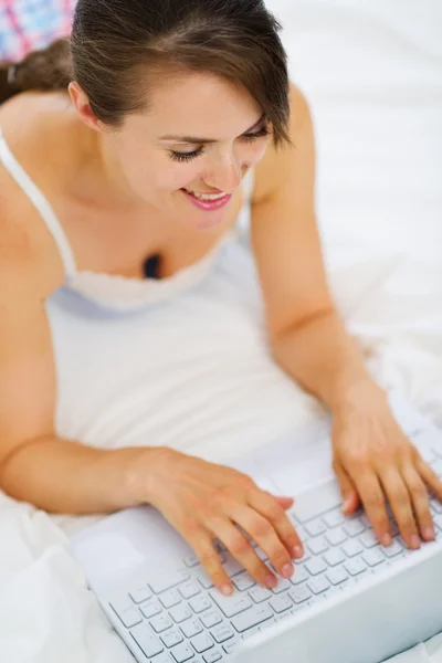 Mujer acostada en la cama y trabajando en el portátil. Vista superior —  Fotos de Stock