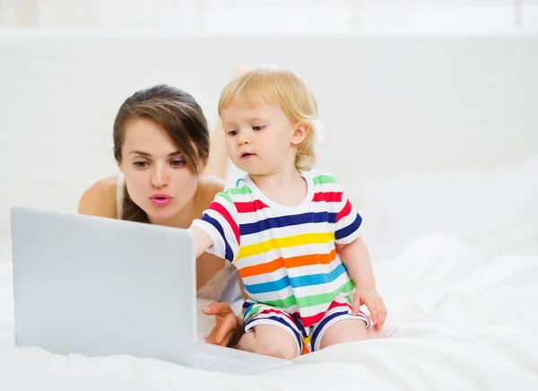 Младенец что-то показывает матери в ноутбуке — стоковое фото