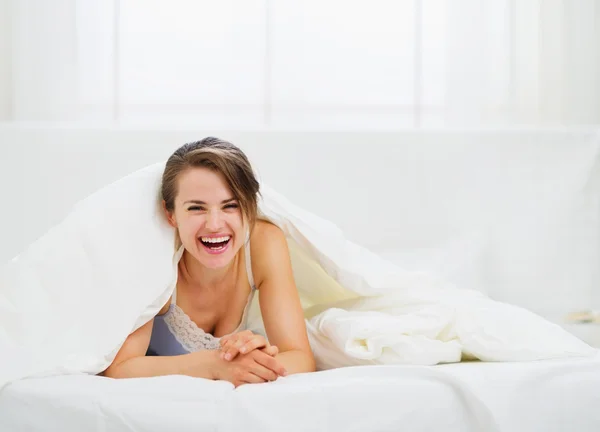 Smiling woman looking out from blanket — Stock Photo, Image