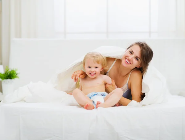 Porträt einer lächelnden Mutter und eines Babys im Schlafzimmer — Stockfoto
