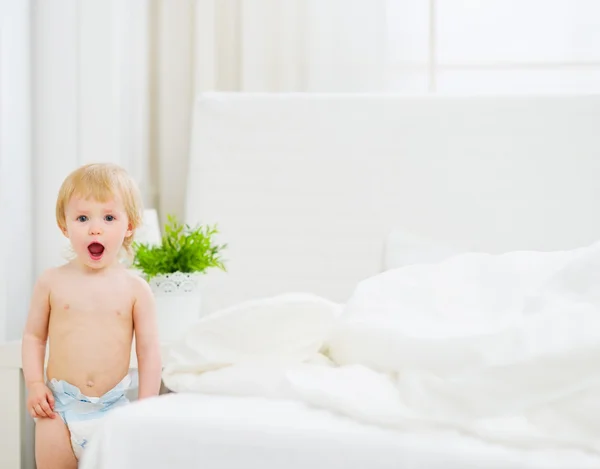 Portrait of surprised baby in bedroom — Stock Photo, Image
