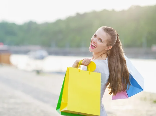 Улыбающаяся женщина с сумками для покупок на набережной — стоковое фото