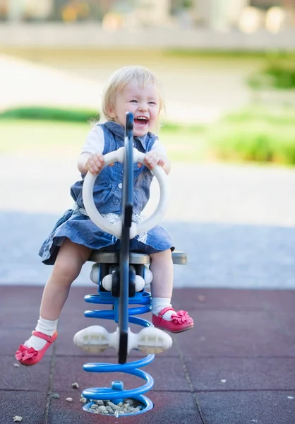 Happy baby swinging on horse on playground — Stock Photo, Image