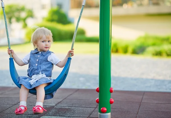 Baby schaukelt auf Schaukel auf Spielplatz. Seitenansicht — Stockfoto