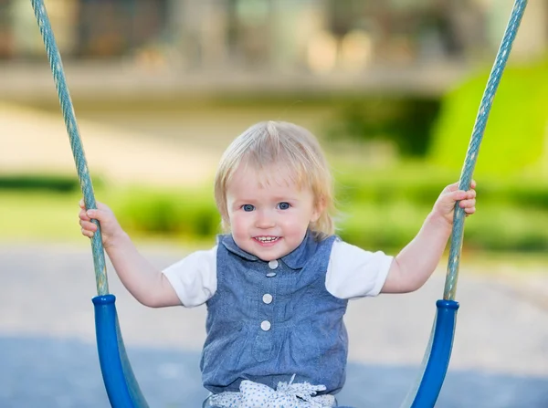 Happy baby sitting on swing — Stock Photo, Image