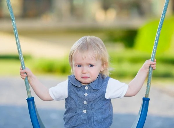 Portrait of unhappy baby sitting on swing — Stock Photo, Image