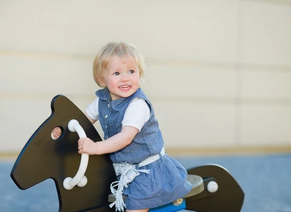 Altalena bambino a cavallo sul parco giochi e guardando sullo spazio copia — Foto Stock