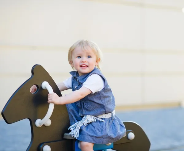 Baby schommel op paard op speelplaats. Zijaanzicht — Stockfoto