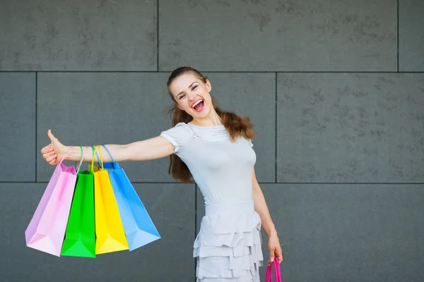 Usmívající se žena s nákupními taškami ukazující palce nahoru — Stock fotografie