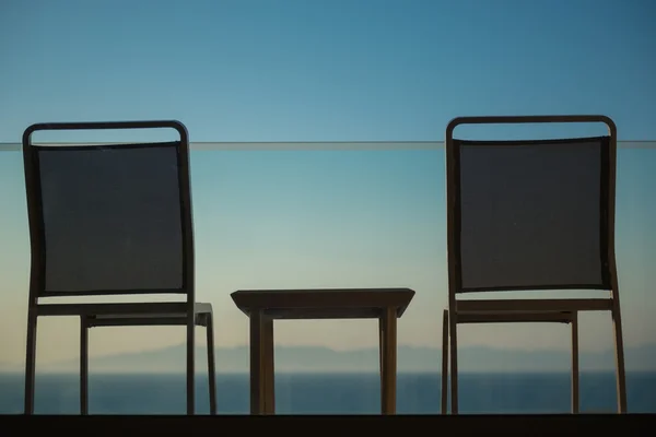 Puesta de sol vista al mar desde balcón con sillas y mesa — Foto de Stock