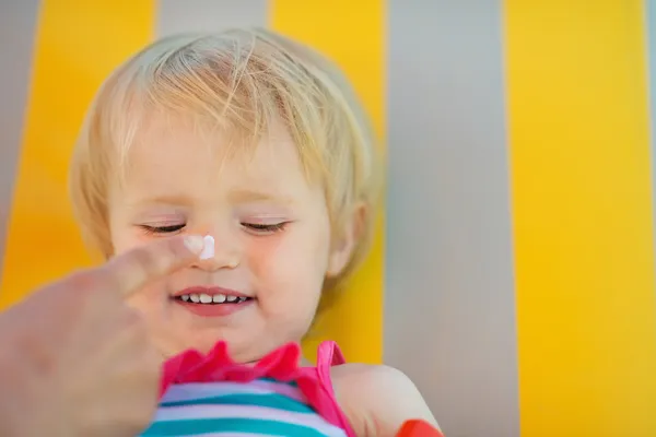 Moederdag hand zon blok crème toepassen op baby neus — Stockfoto