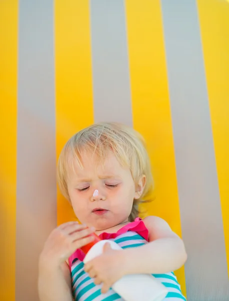 Baby laying on sunbed and using sun screen creme — Stock Photo, Image