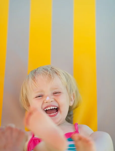 Портрет смеющегося ребенка с кремом от загара на носу — стоковое фото