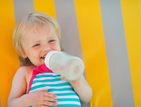 Portrait of happy baby laying on sunbed and drinking water — Stock Photo, Image