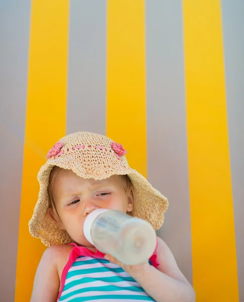 Baby laying on sun bed and drinking from bottle — Stock Photo, Image