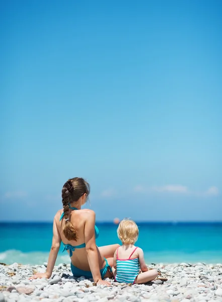 Anne bebek ile mesafe içine bakarak sahilde oturuyor. vi arka — Stok fotoğraf