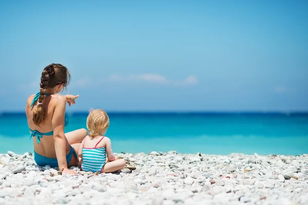 Matka siedzi z dzieckiem na brzegu morza, patrząc na odległość. Rea — Zdjęcie stockowe