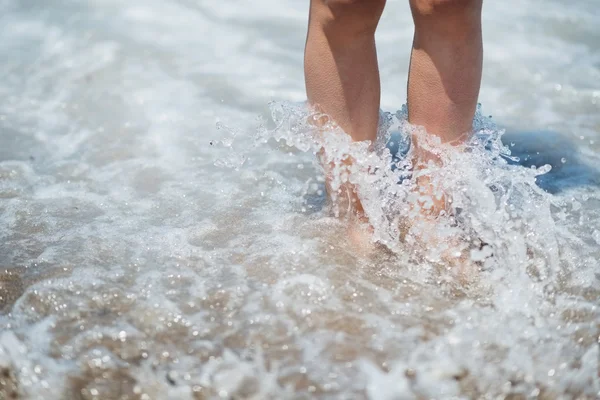 Close-up em pernas em salpicos de onda do mar — Fotografia de Stock