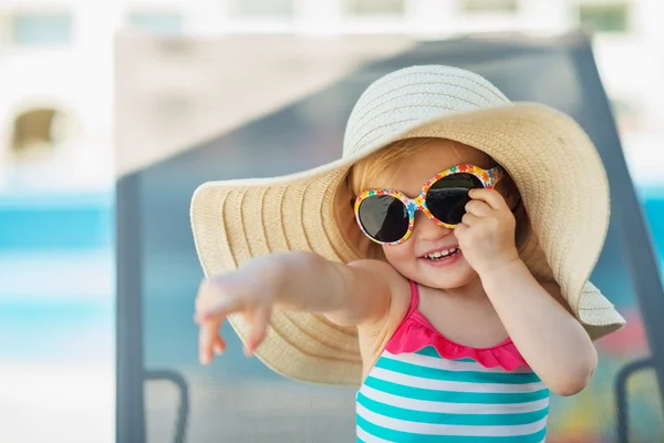 Portrait of baby in hat and glasses pointing in corner — Stock Photo, Image