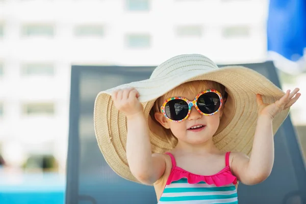 Retrato de bebé en sombrero y gafas sentado en la cama de sol —  Fotos de Stock