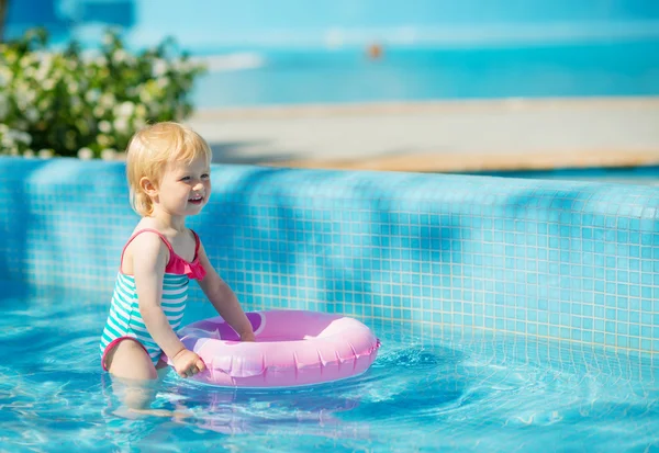 Bebê de pé na piscina com anel inflável — Fotografia de Stock
