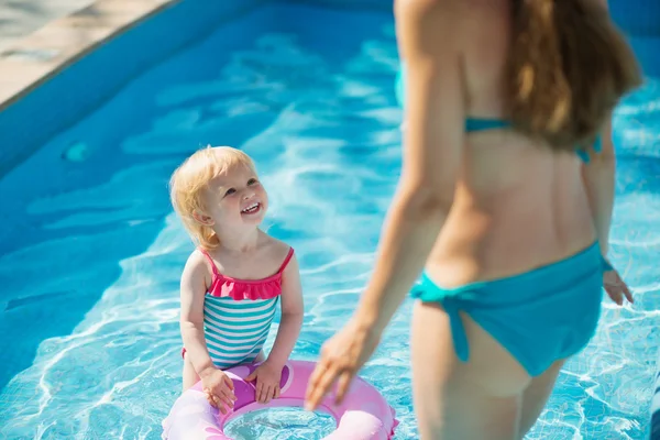 Ребенок стоит в бассейне с надувным кольцом и смотрит на мать — стоковое фото