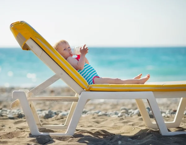 Baby laying on sunbed and drinking water — Stock Photo, Image