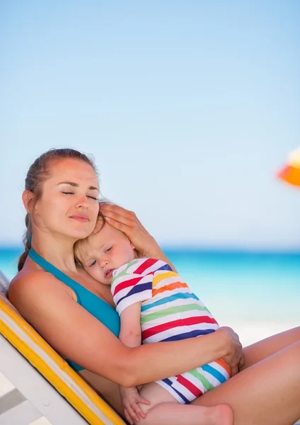 Moeder en baby ontspannen op zonnebank op strand — Stockfoto