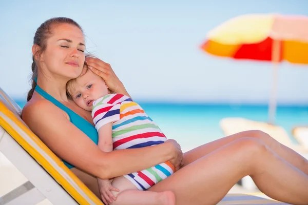 Relajada madre en la cama de sol abrazando al bebé — Foto de Stock