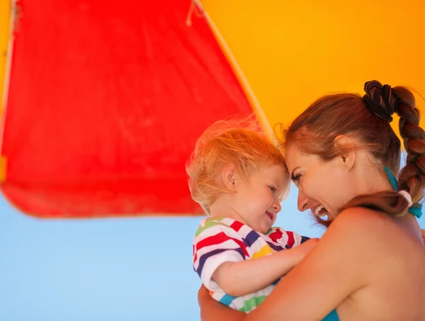 妈妈和宝宝在伞下的海滩上的肖像 — 图库照片