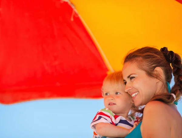 Happy mother and kid looking on copy space on beach — Stock Photo, Image