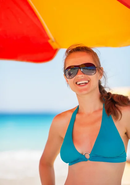 Portret van lachende vrouw op strand onder de paraplu — Stockfoto