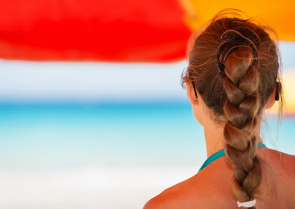 Frau am Strand unter Sonnenschirm und Blick in die Ferne. Rückansicht — Stockfoto