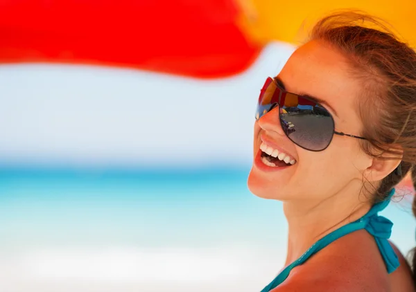 Портрет улыбающейся женщины на пляже под зонтиком — стоковое фото