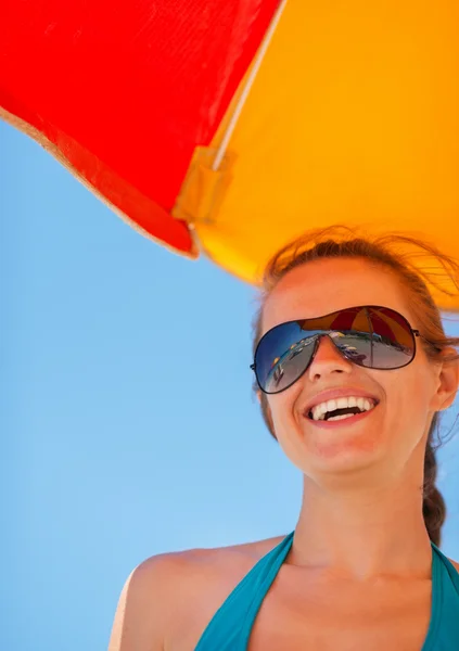 Портрет улыбающейся девушки на пляже под зонтиком — стоковое фото