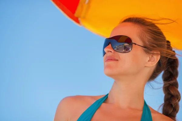 Happy woman in sunglasses on windy beach looking on copy space — Zdjęcie stockowe