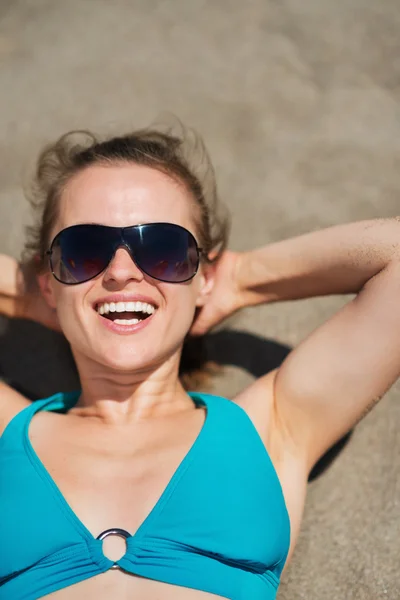 Portret van lachende vrouw opleggen zandstrand — Stockfoto