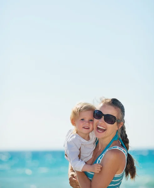 Portræt af glad mor og baby på stranden - Stock-foto