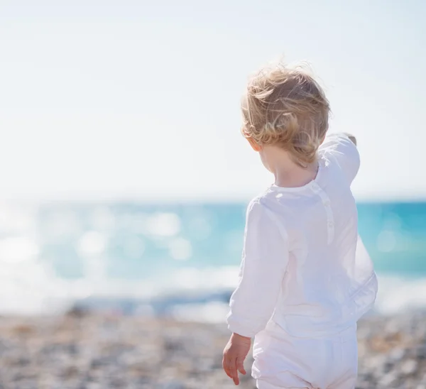 Ребенок на пляже, указывая вдаль — стоковое фото