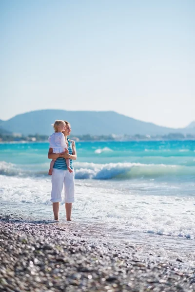 Anne ile bebek mesafe içine bakarak deniz kenarı — Stok fotoğraf