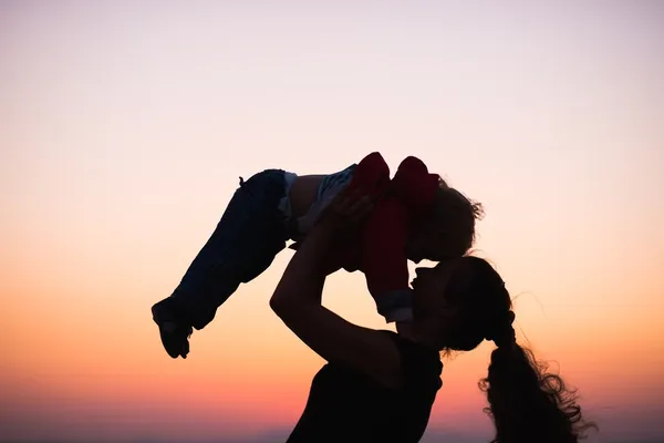 Silhouette einer Mutter, die in der Dämmerung mit Baby spielt — Stockfoto