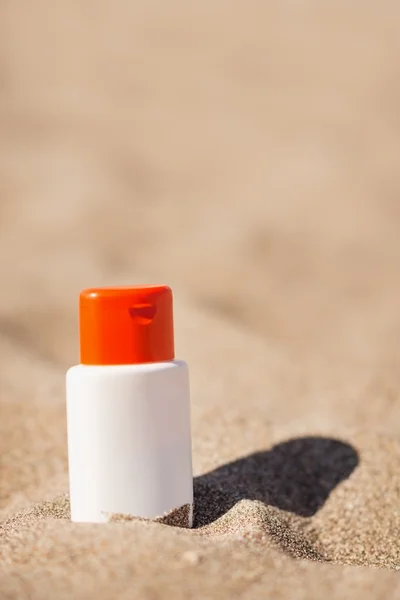 Garrafa de creme protetor solar na areia — Fotografia de Stock