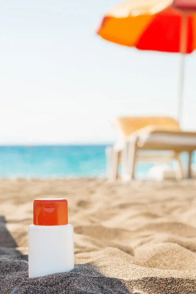 Бутылка крема от солнца в тени на пляже — стоковое фото