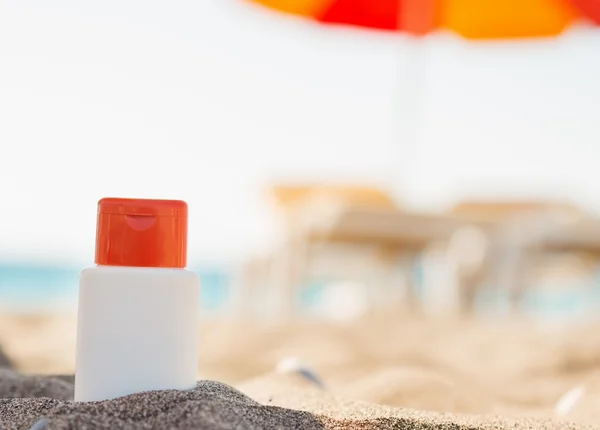 Bottiglia di crema solare in ombra sulla spiaggia — Foto Stock